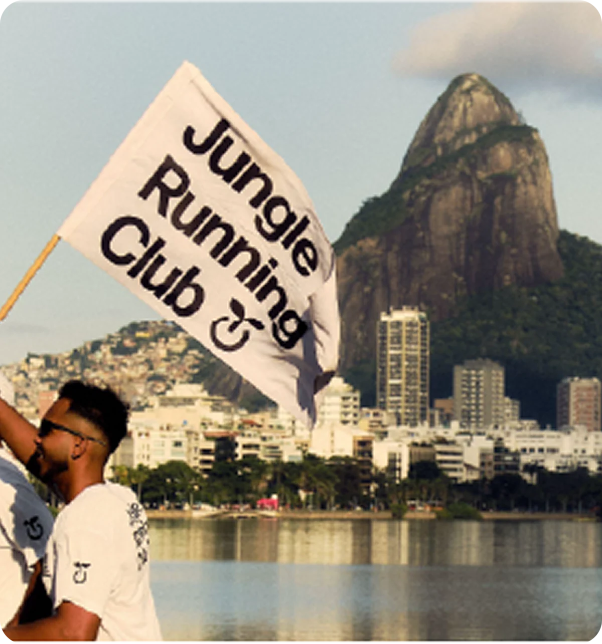Pessoa segurando uma bandeira do Jungle Running Club diante do Pão de Açúcar